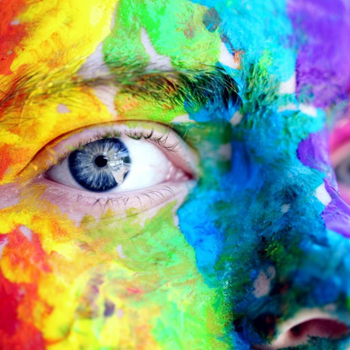 Close-up of a person with colorful rainbow face paint, symbolizing LGBT pride and expression.